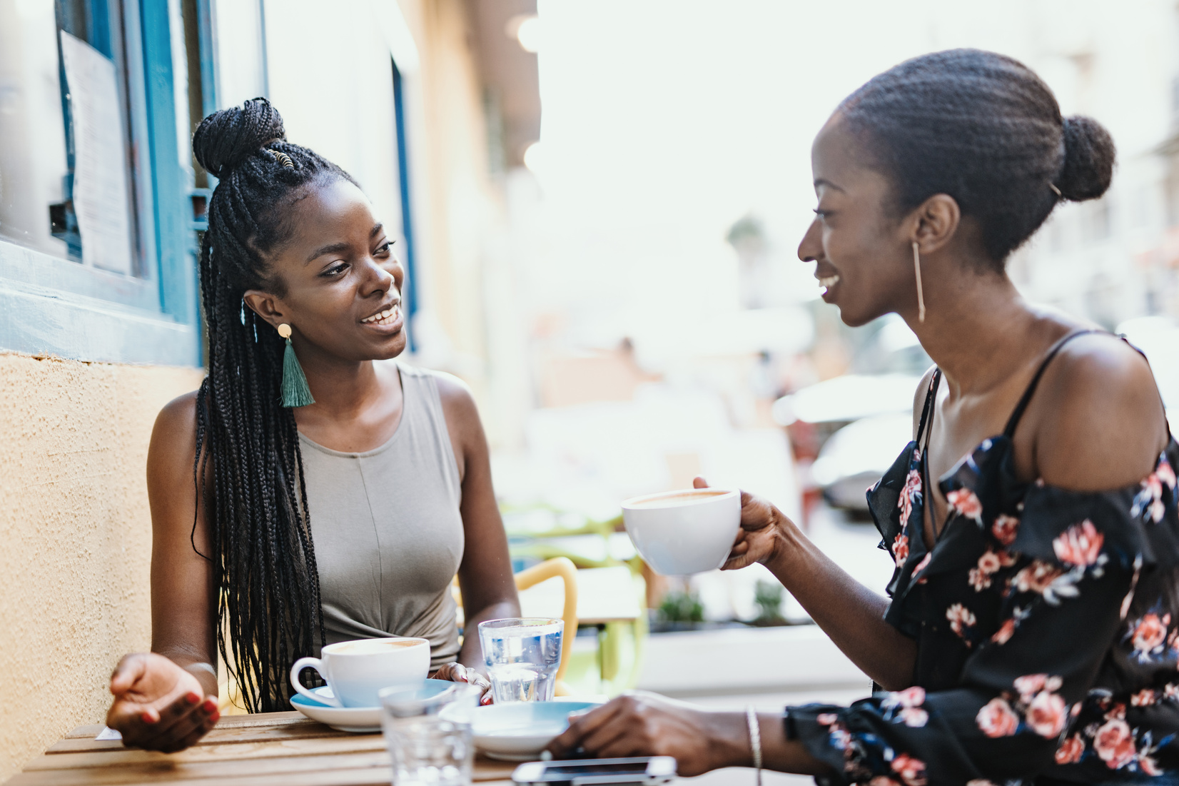 African millennial women drinking coffee outdoors